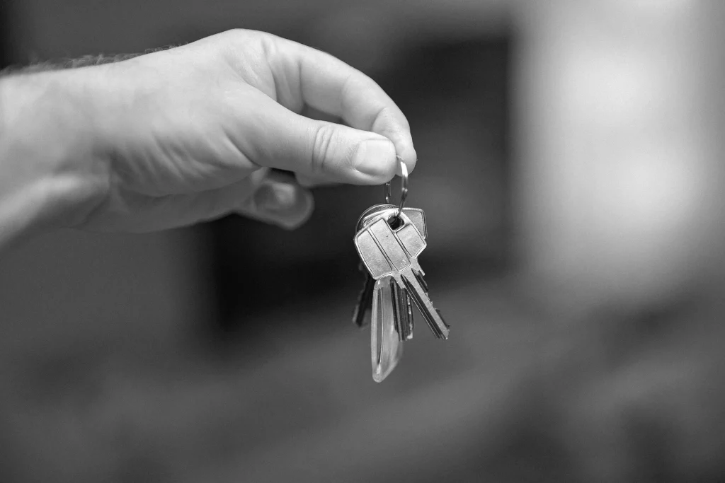 Dłoń trzymająca pęk kluczy na kółku na rozmytym tle.