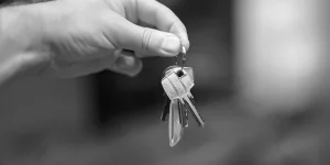 Dłoń trzymająca pęk kluczy na kółku na rozmytym tle.